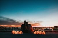 Couple sitting together watching the sunset over a city skyline