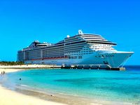 Cruise ship docked near a turquoise Caribbean beach